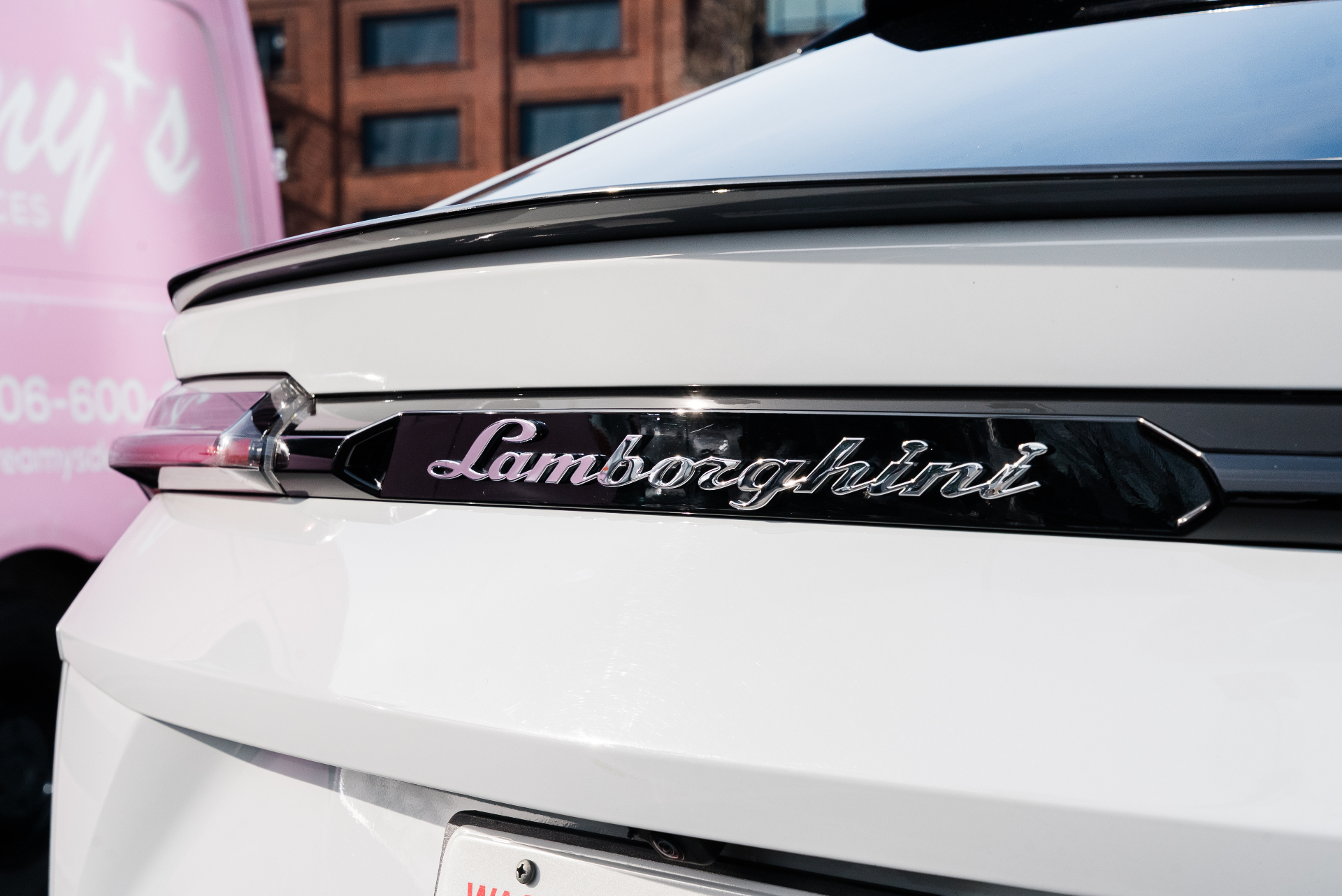 Lamborghini badge detail on a freshly detailed white Urus next to the pink Dreamy's van