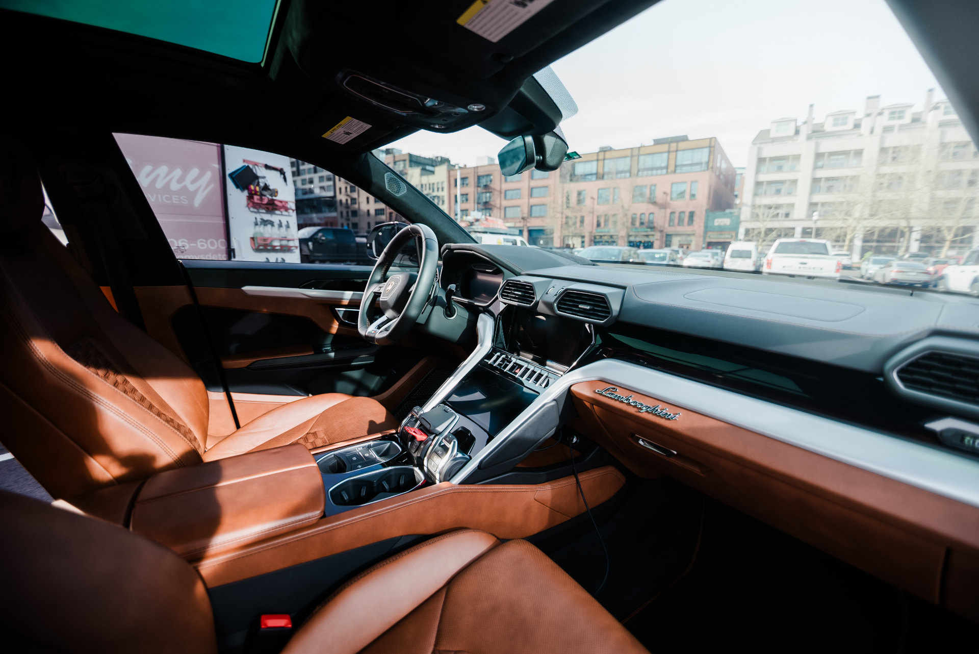 An immaculate detailed luxury car interior with polished wood trim and conditioned tan leather.